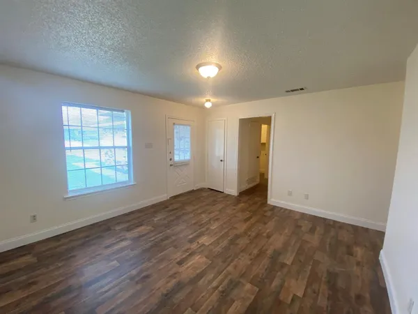 an empty room with wooden floor and windows