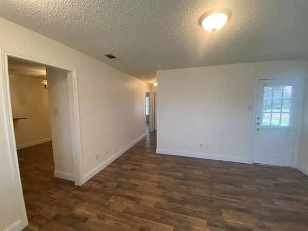 an empty room with wooden floor and entrance