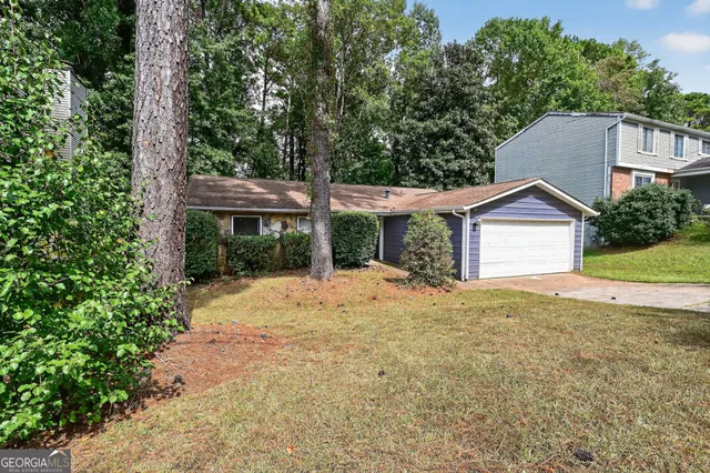 a view of a house with a yard and large tree