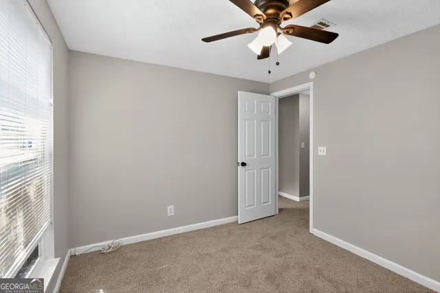 an empty room with a window and a ceiling fan