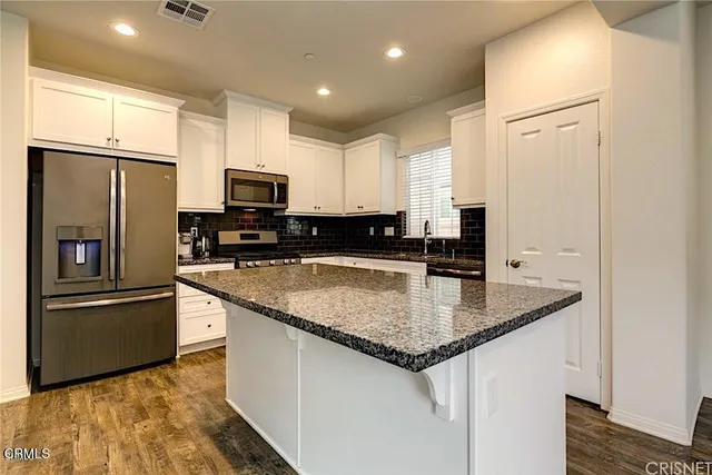 a kitchen with stainless steel appliances granite countertop a refrigerator a stove a sink and a microwave