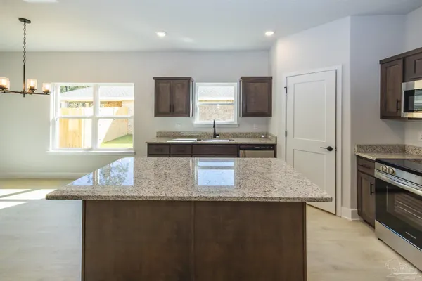 a kitchen with stainless steel appliances granite countertop a stove top oven a sink and a microwave