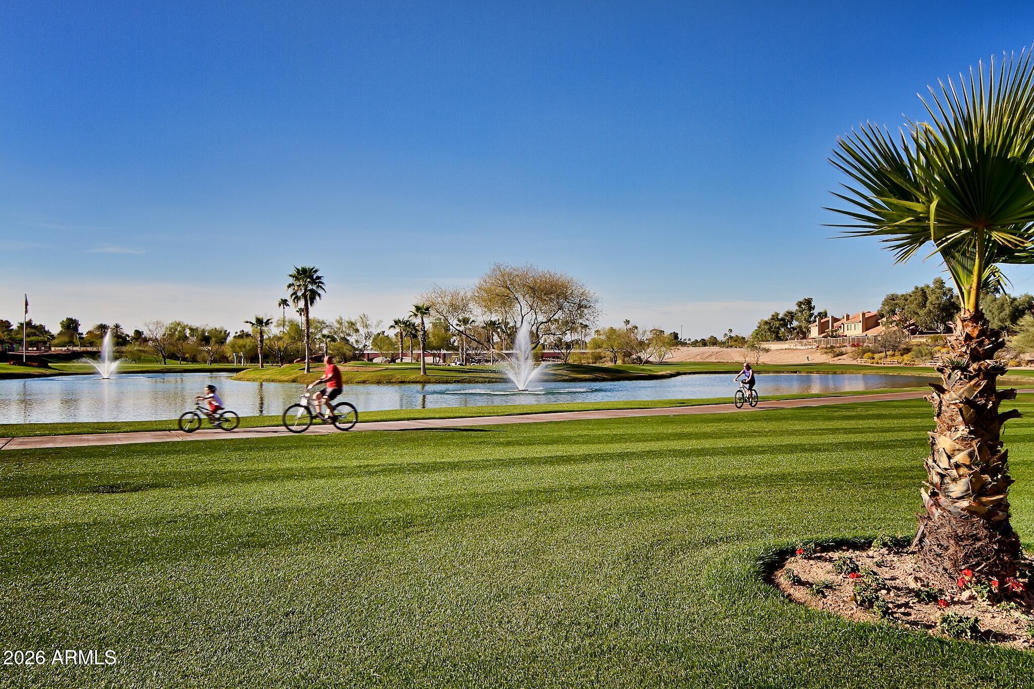 a view of a fountain in front of a big house with a big yard