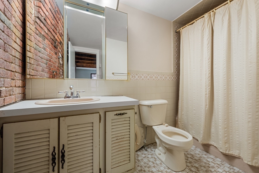 170 Commercial Street, Unit 4 Boston, MA 02109 - Photo 8 of 18 a bathroom with a sink a toilet a mirror and shower curtain