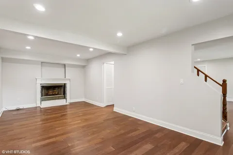 a view of an empty room with wooden floor fireplace and a window