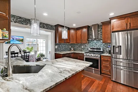 a kitchen with stainless steel appliances granite countertop a sink a stove and a refrigerator