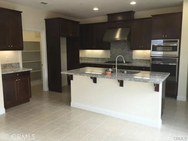 a large kitchen with a large counter top stainless steel appliances and cabinets