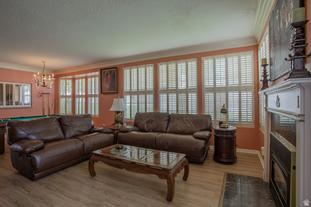 5302 South Birch Pt Road Murray, UT 84117 - Photo 15 of 29 Recessed fireplace with white mantel, wood-finish flooring, multiple windows with plantation shutters, and crown molding