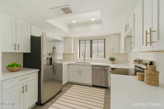 a kitchen with a sink dishwasher a refrigerator and white cabinets with wooden floor