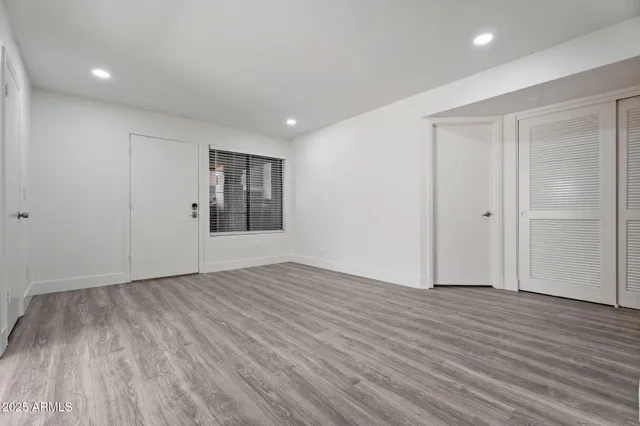 a view of an empty room with wooden floor and window