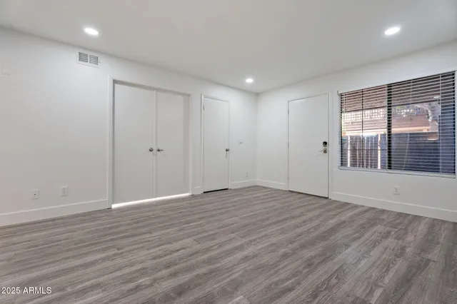 an empty room with wooden floor and windows