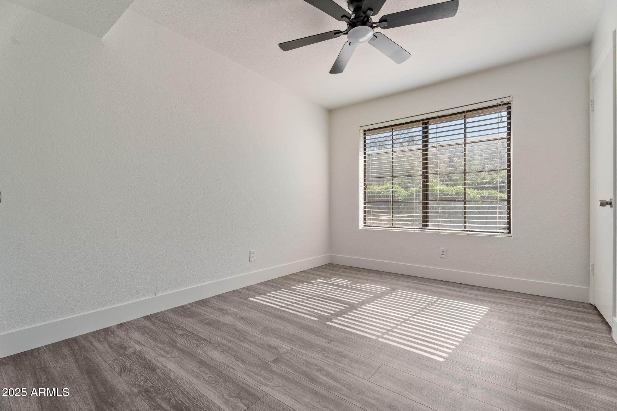1905 East University Drive, Unit 133 Tempe, AZ 85288 - Photo 21 of 38 a view of an empty room with wooden floor and a window