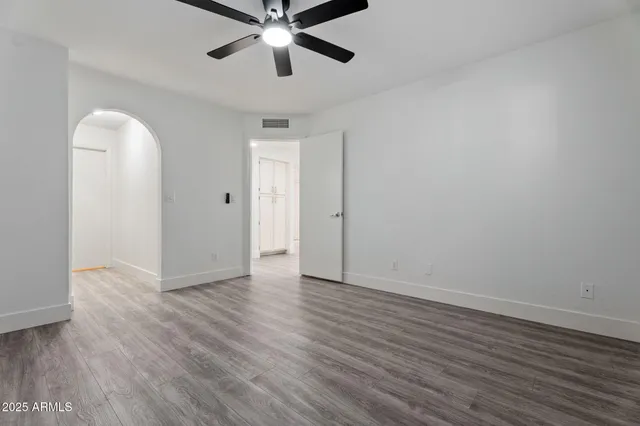 an empty room with wooden floor chandelier fan and closet area