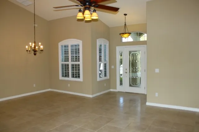 an empty room with windows and ceiling fan