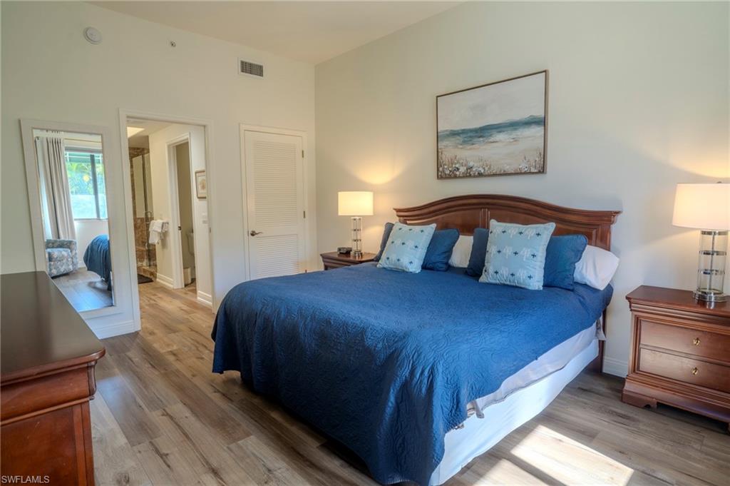 1045 Sandpiper Street, Unit G204 Naples, FL 34102 - Photo 14 of 40 a bedroom with a bed and a mirror