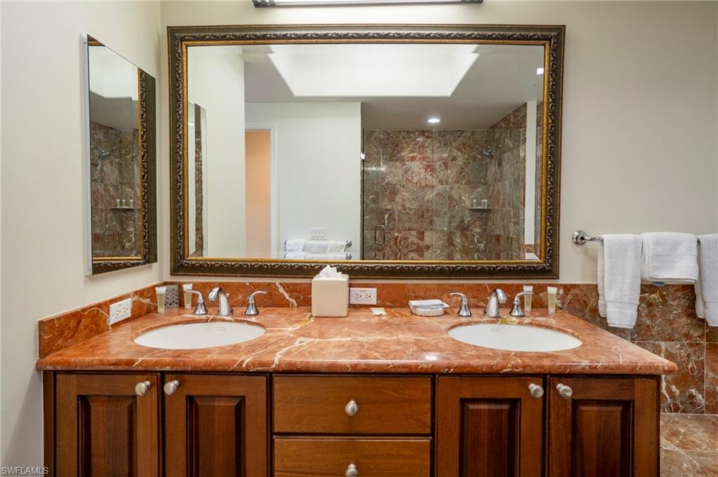 1045 Sandpiper Street, Unit G204 Naples, FL 34102 - Photo 15 of 40 a bathroom with a granite countertop sink a mirror and a shower