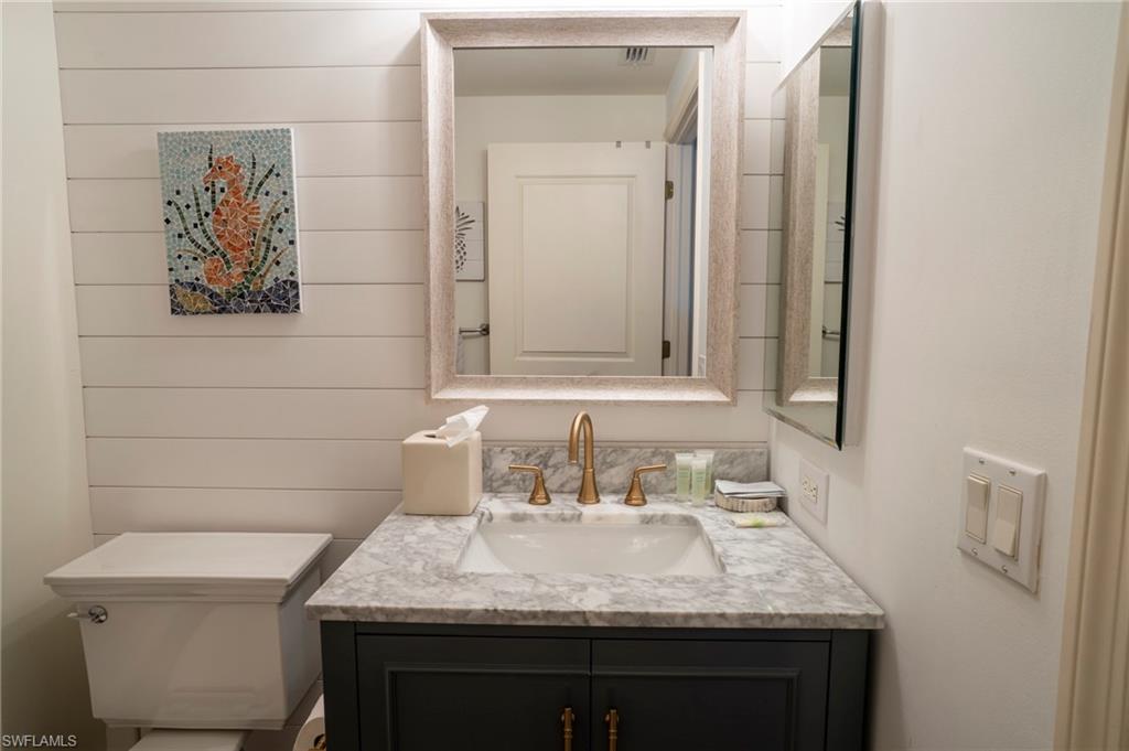 1045 Sandpiper Street, Unit G204 Naples, FL 34102 - Photo 18 of 40 a bathroom with a granite countertop sink and a toilet