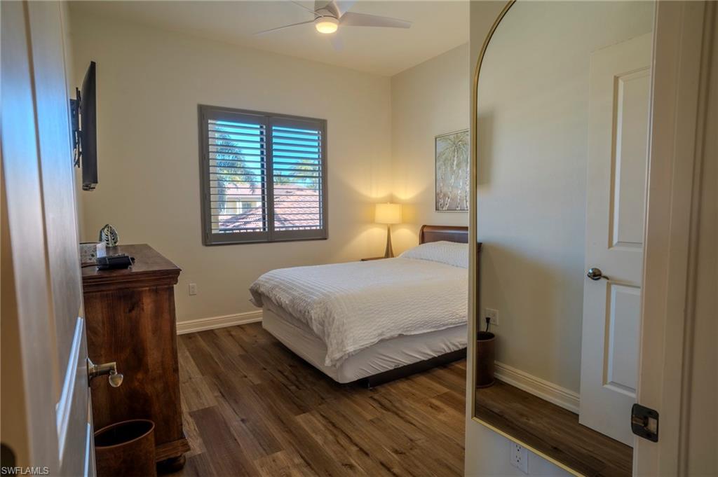 1045 Sandpiper Street, Unit G204 Naples, FL 34102 - Photo 20 of 40 a bedroom with a bed and wooden floor