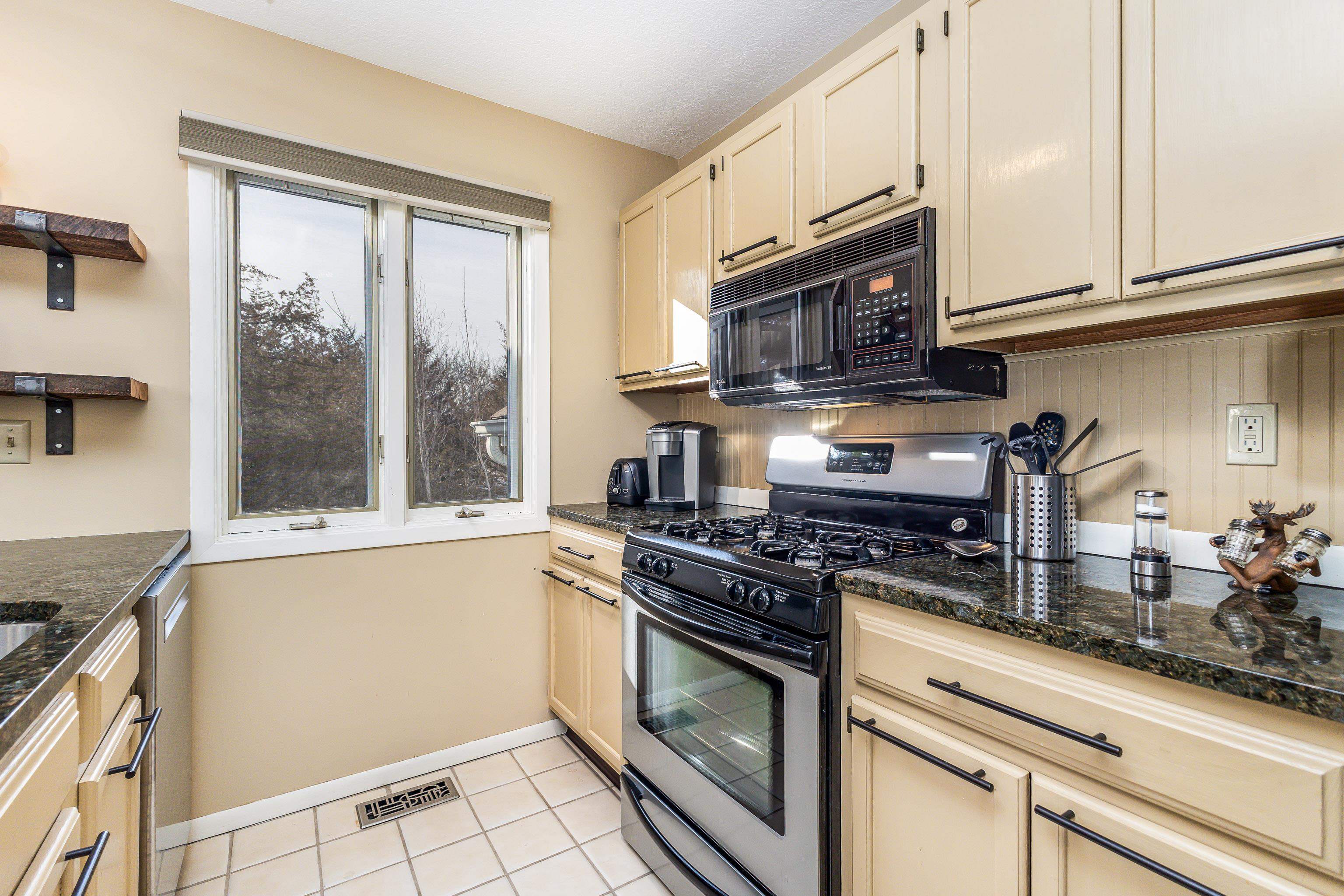 a kitchen with stainless steel appliances granite countertop a stove a sink and a microwave