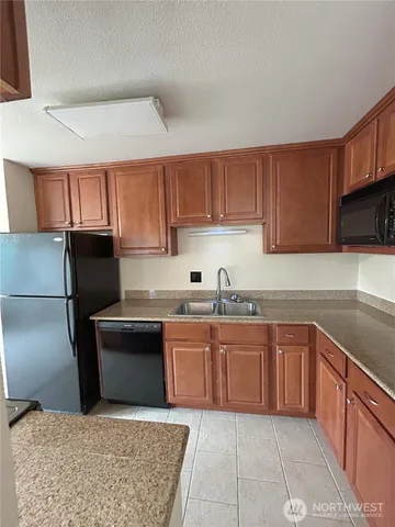a kitchen with granite countertop a sink dishwasher stove and cabinets