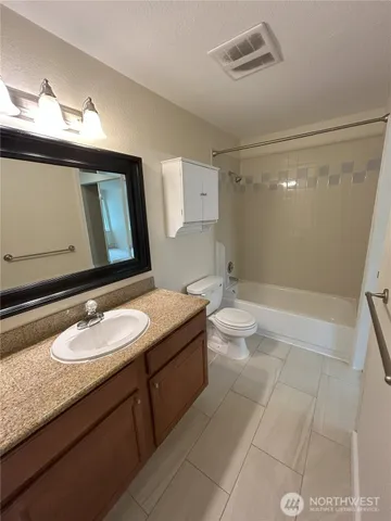 a bathroom with a granite countertop sink a toilet a mirror and shower