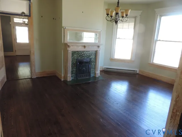an empty room with wooden floor fireplace and windows