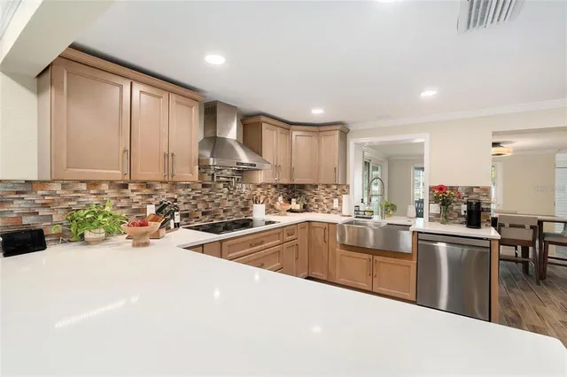 a kitchen with stainless steel appliances a sink a stove a refrigerator cabinets and a dining table