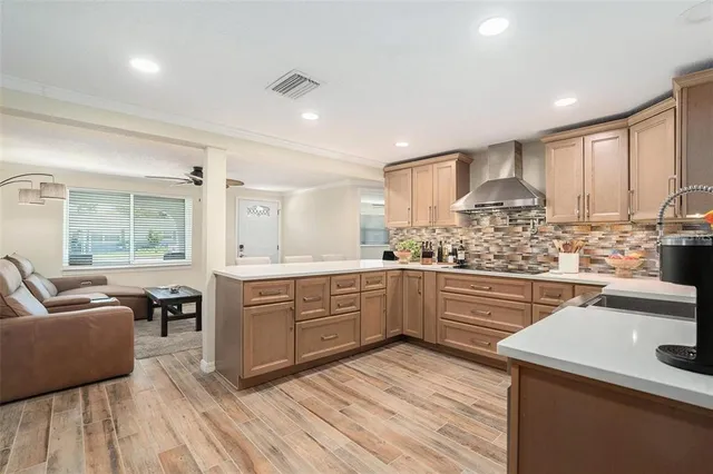 a kitchen with stainless steel appliances kitchen island granite countertop a sink dishwasher stove and white cabinets with wooden floor