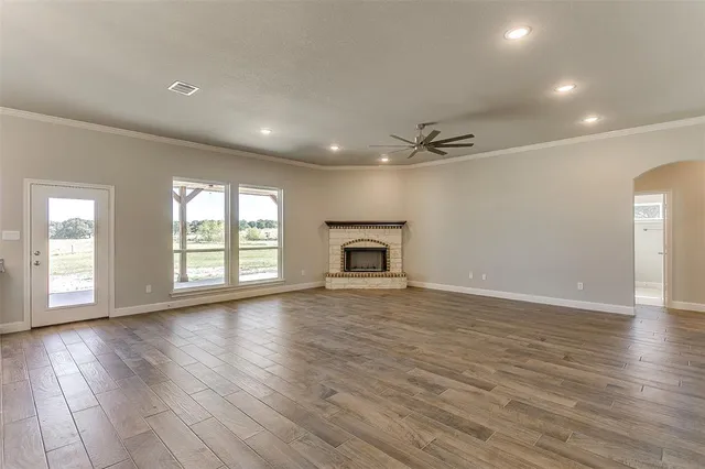an empty room with wooden floor fireplace and windows