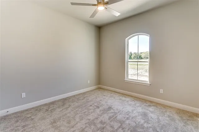 an empty room with chandelier fan and windows