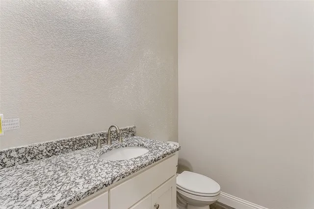 a bathroom with a granite countertop sink toilet and a mirror