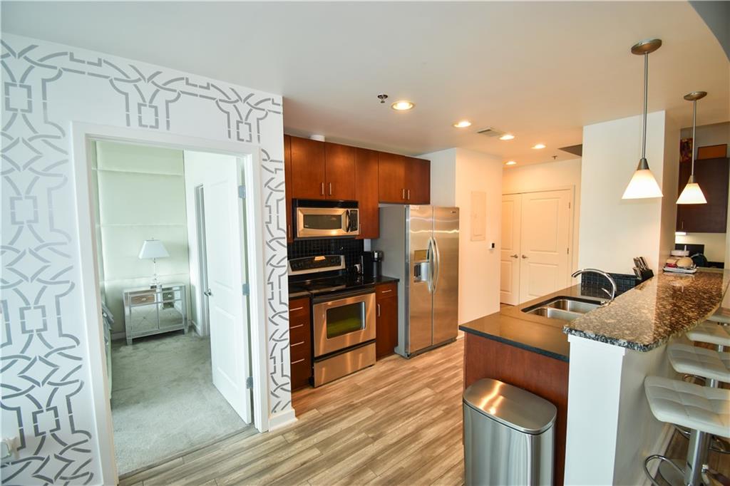 250 Pharr Road Northeast, Unit 1103 Atlanta, GA 30305 - Photo 5 of 16 a kitchen with stainless steel appliances kitchen island granite countertop a refrigerator and a stove top oven