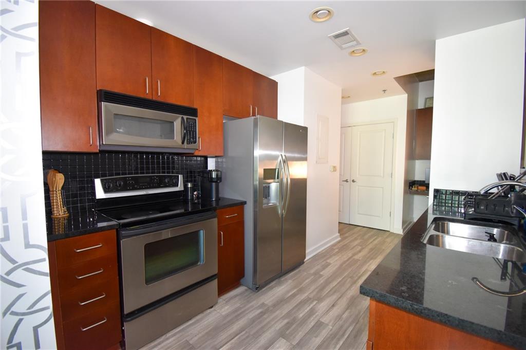 250 Pharr Road Northeast, Unit 1103 Atlanta, GA 30305 - Photo 6 of 16 a kitchen with stainless steel appliances granite countertop a stove a refrigerator and a microwave