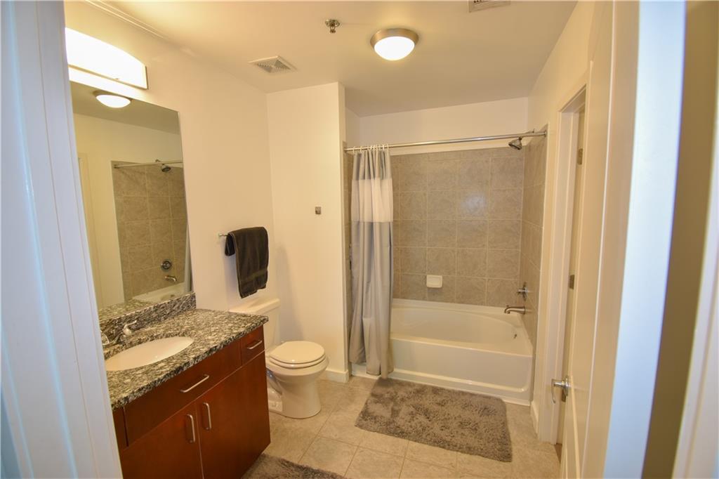 250 Pharr Road Northeast, Unit 1103 Atlanta, GA 30305 - Photo 9 of 16 a bathroom with a granite countertop sink toilet and shower