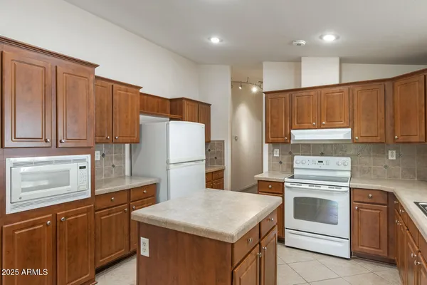 a kitchen with kitchen island granite countertop wooden cabinets and white appliances