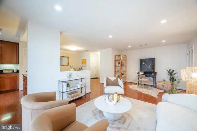 a living room with furniture kitchen view and a wooden floor