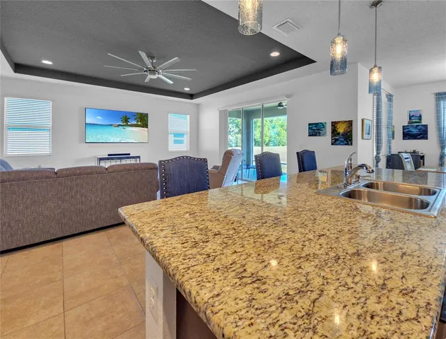 a large kitchen with kitchen island a stove a sink a dining table and chairs with the bookshelf