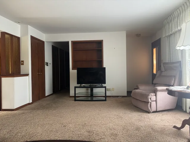 a living room with furniture a flat screen tv and gym equipment