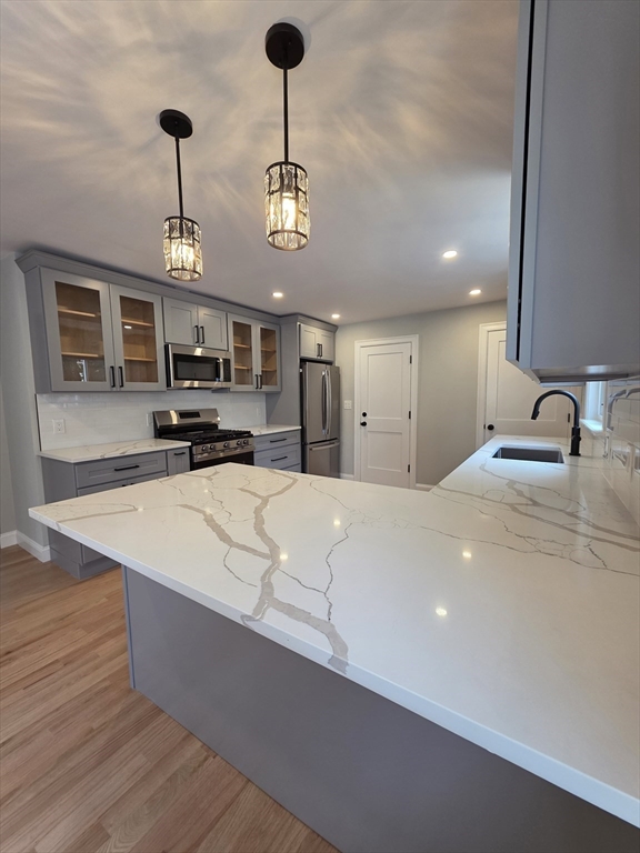 a large kitchen with stainless steel appliances a large counter top a stove and a sink with chandelier