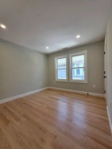 a view of an empty room with wooden floor and window