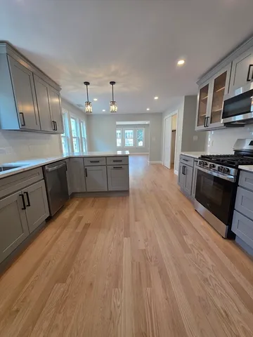 a large kitchen with wooden floors and stainless steel appliances