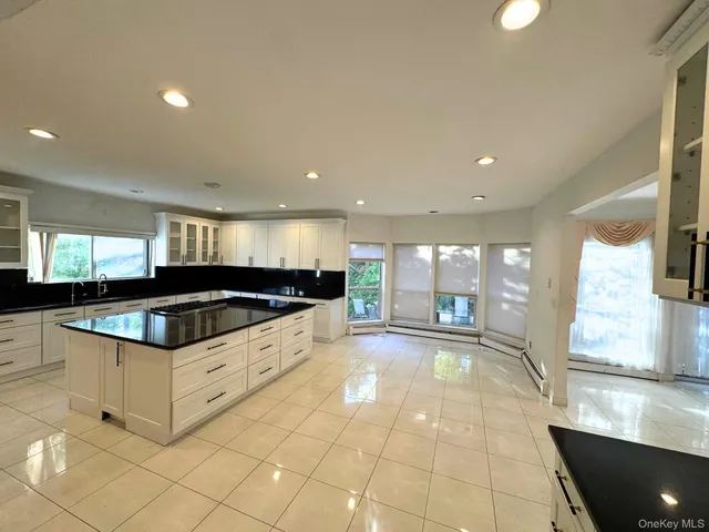 a large white kitchen with kitchen island granite countertop a stove a sink and a refrigerator