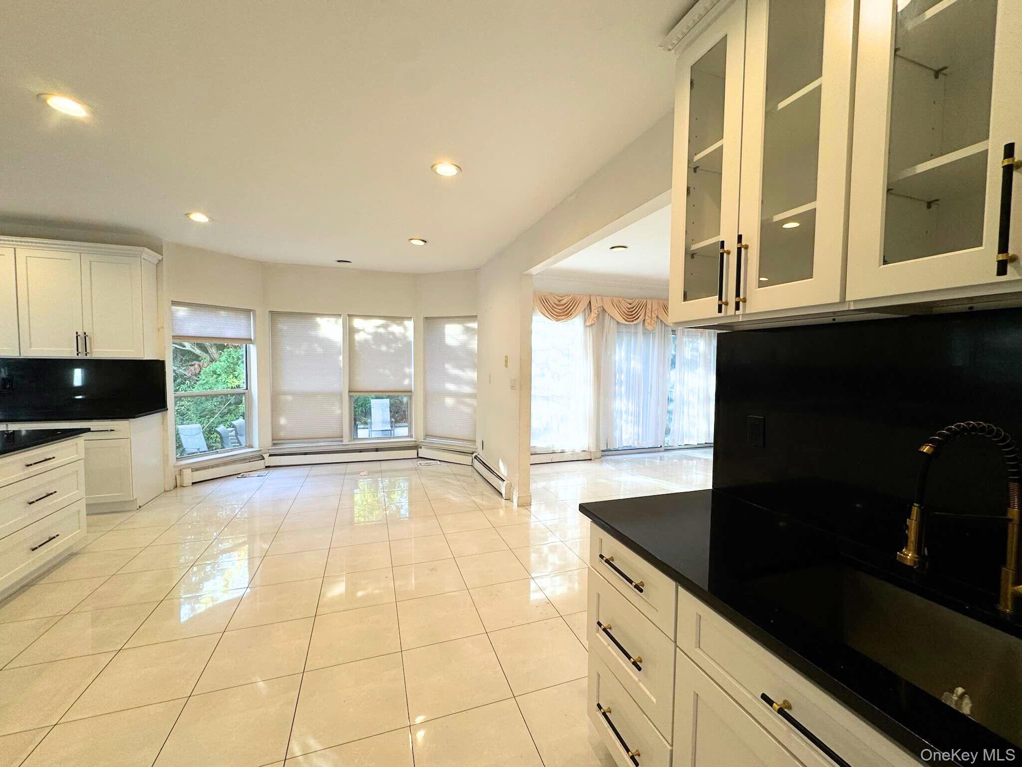 21 Cary Road Great Neck, NY 11021 - Photo 13 of 17 Kitchen featuring light tile patterned floors, recessed lighting, white cabinetry, glass insert cabinets, and dark stone counters