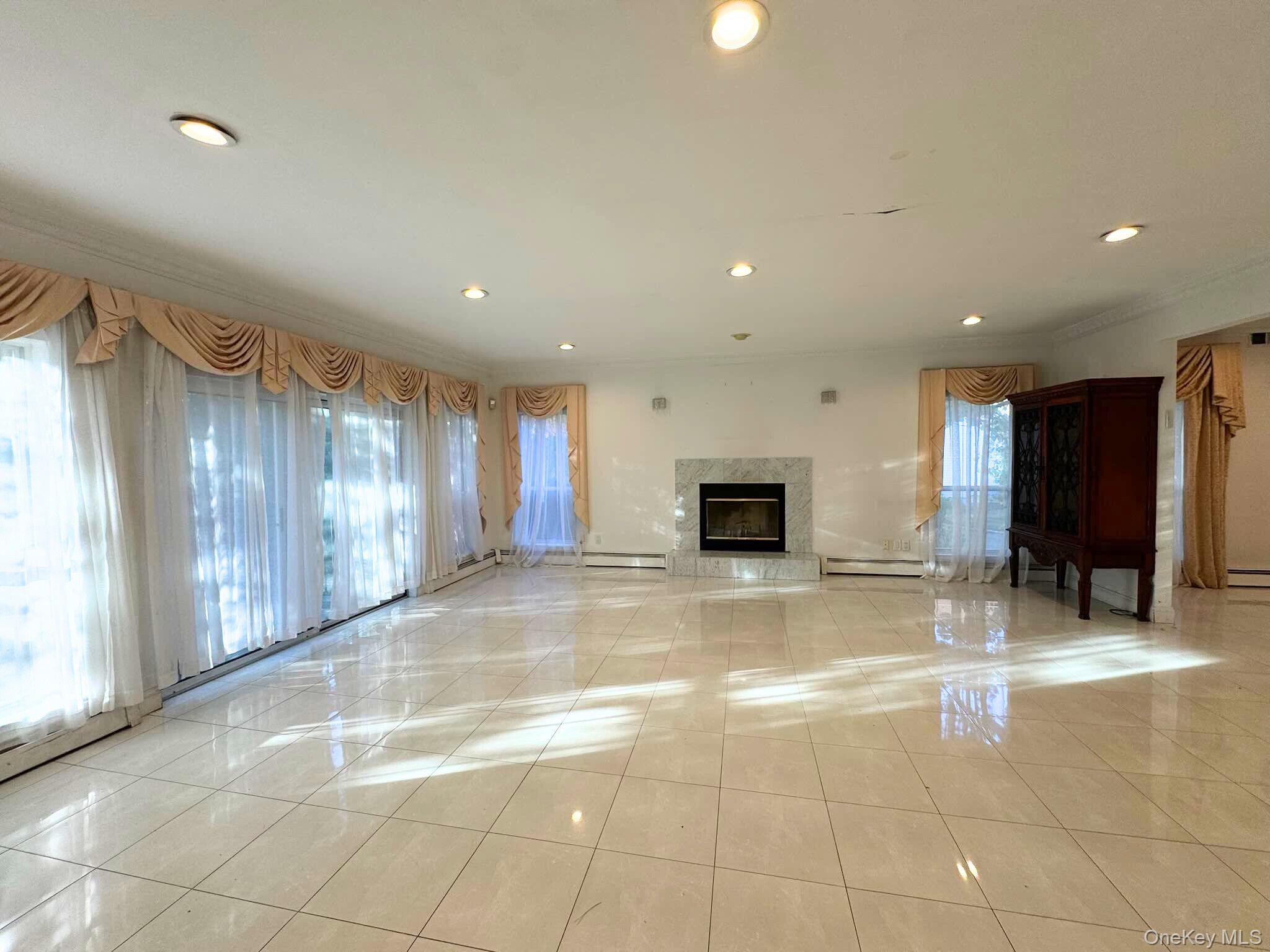 21 Cary Road Great Neck, NY 11021 - Photo 15 of 17 Unfurnished living room with a high end fireplace, recessed lighting, light tile patterned floors, ornamental molding, and a baseboard heating unit