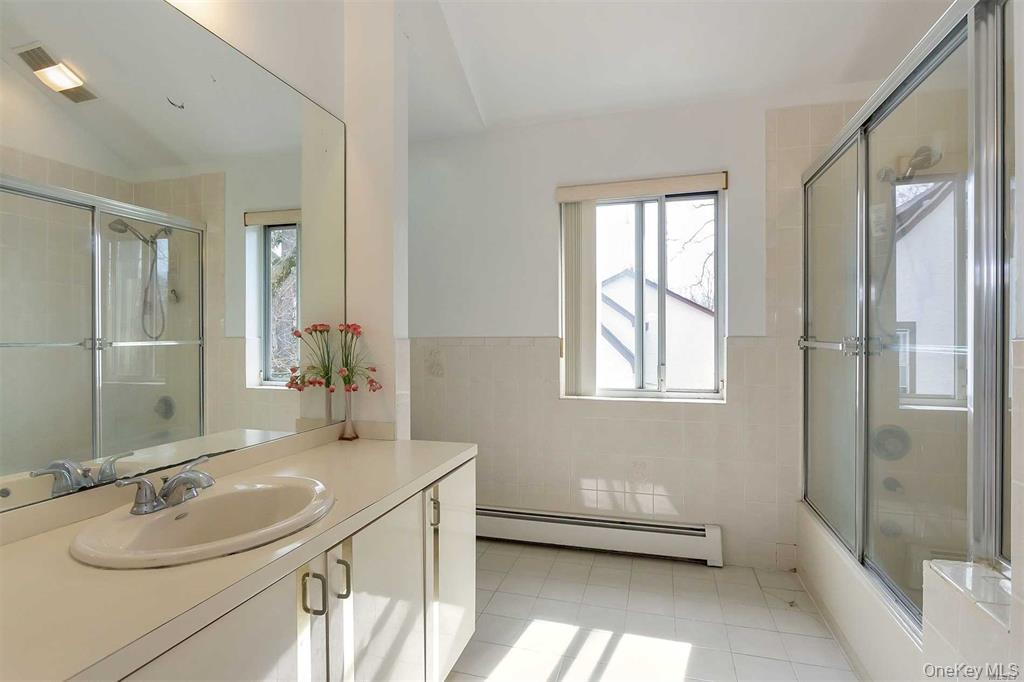 21 Cary Road Great Neck, NY 11021 - Photo 6 of 17 Full bath with vanity, tile walls, baseboard heating, healthy amount of natural light, and light tile patterned floors