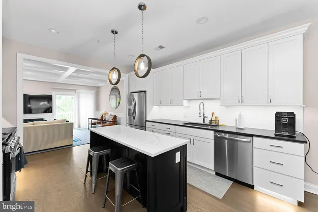 a kitchen with a sink a stove chandelier and wooden floor