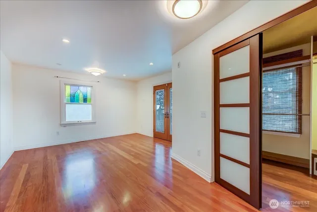 a view of an empty room with wooden floor and a window