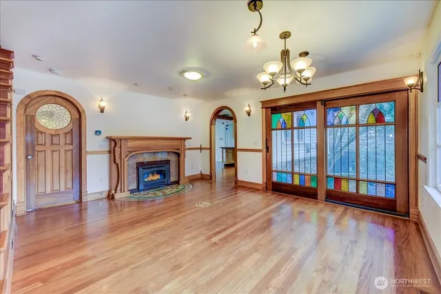 a view of an empty room with wooden floor fireplace and a window