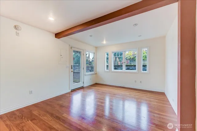an empty room with wooden floor and windows