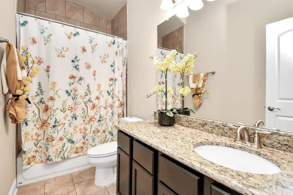 a bathroom with a granite countertop sink a toilet and a mirror